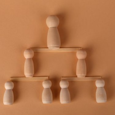 Wooden peg dolls arranged in a pyramid, symbolizing leadership and teamwork.