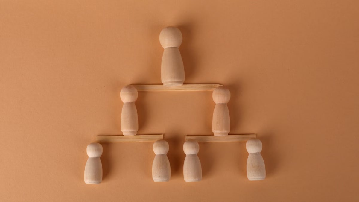 Wooden peg dolls arranged in a pyramid, symbolizing leadership and teamwork.