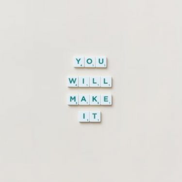 Motivational phrase 'You Will Make It' made from Scrabble tiles on a neutral background.