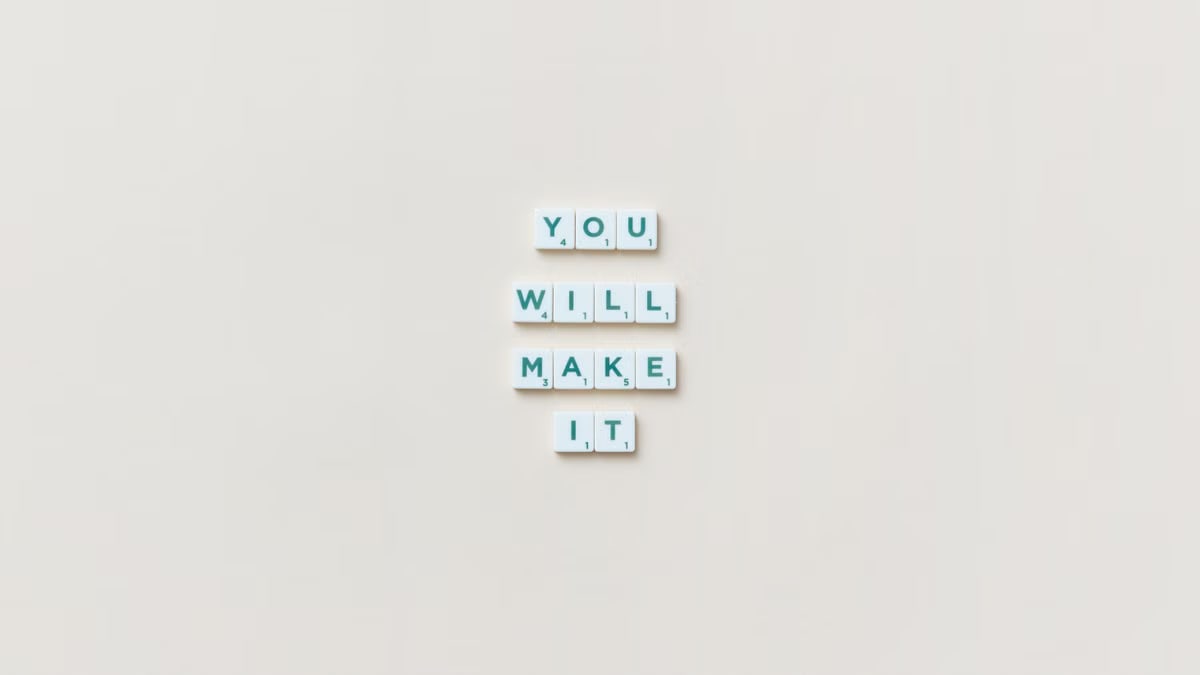 Motivational phrase 'You Will Make It' made from Scrabble tiles on a neutral background.